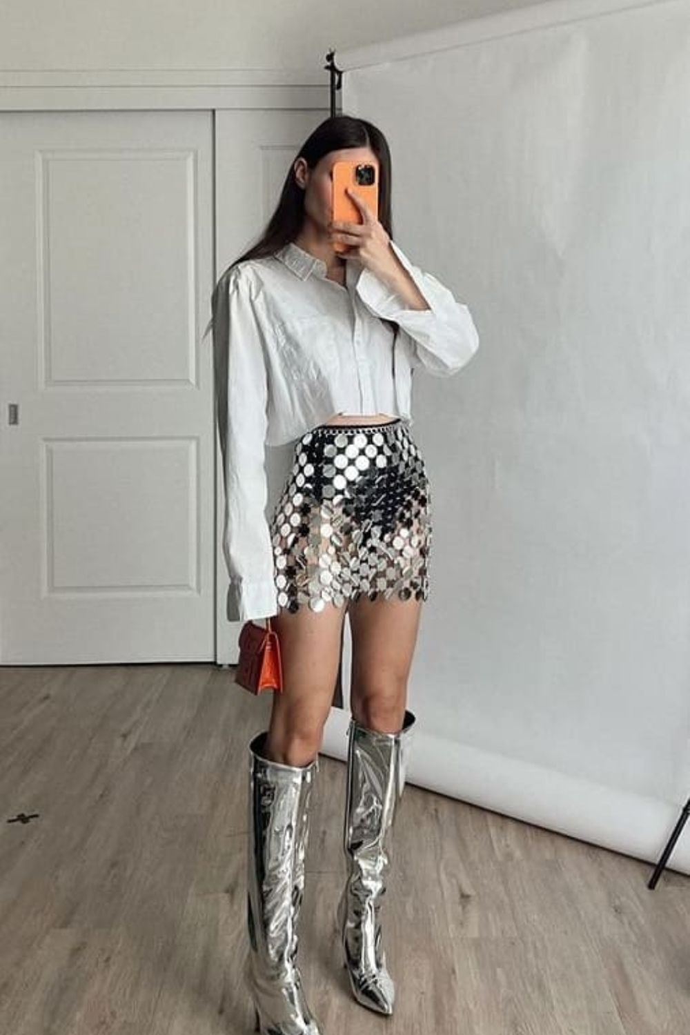 silver skirt, white crop button up long sleeve top, silver knee high boots, orange mini purse